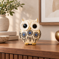 Aegis evil-eye owl figurine styled on a warm walnut living-room console