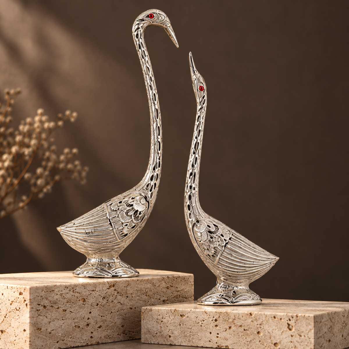 Ornate silver swan pair displayed on travertine plinths