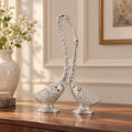 Silver metal swan pair styled on a walnut console