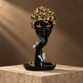 Black face sculpture with gold floral crown and silver butterflies