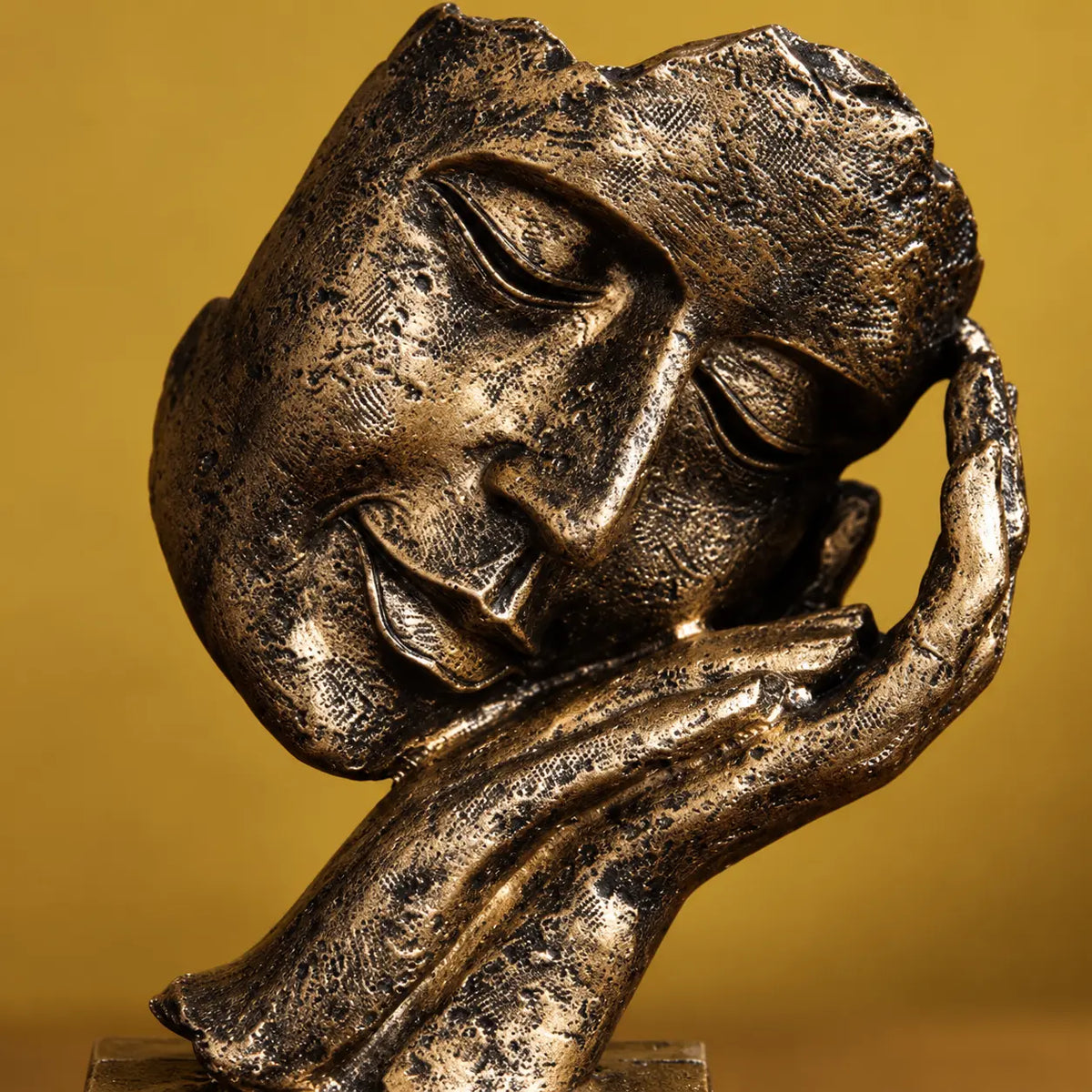 Close view of the serene face, sculpted hand and antique-gold patina