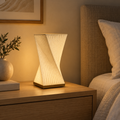 Helix Glow sculptural table lamp casting warm light on a light wood bedside table