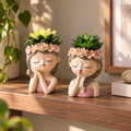 Quiet Muse woman bust succulent planters styled on a warm walnut living-room shelf