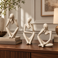 Cream abstract seated figurines styled on a walnut console