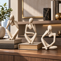 Set of three contemplative resin figurines in an office interior